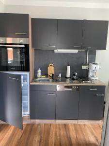 a kitchen with black cabinets and a sink at Zum Kölpiensee in Peenemünde