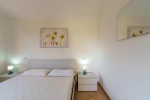 a white bedroom with a bed and two night stands at Casa Vacanze Susino in Olbia
