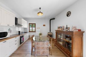 a kitchen with white cabinets and a table with chairs at Casa Loppia 2022 in Caprino Veronese