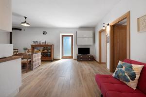 a living room with a red couch and a kitchen at Casa Loppia 2022 in Caprino Veronese