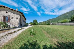 an old stone building with a field next to it at Casa Loppia 2022 in Caprino Veronese