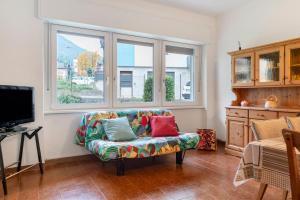 a living room with a couch and two windows at Appartamento Spormaggiore in Spormaggiore
