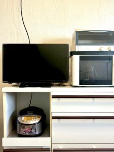 a television and a microwave on a white shelf at 明月民宿 in Takatsuki
