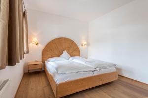 a bedroom with a large bed with a wooden headboard at Sabina Dolomites Compatsch in Alpe di Siusi +25 photos