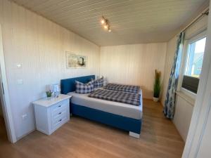 a small bedroom with a blue bed and a window at Skipper Hus by Seeblick Ferien in Olpenitz