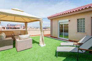 a patio with a lawn with chairs and an umbrella at Casa Limón in Puerto Marino