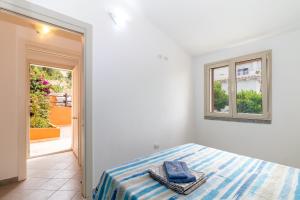ein weißes Schlafzimmer mit einem Bett und einem Fenster in der Unterkunft Casa Angus in Badesi