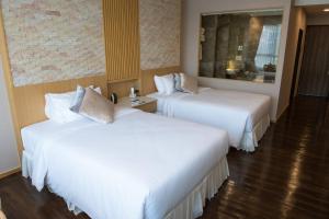 2 Betten in einem Hotelzimmer mit weißer Bettwäsche in der Unterkunft North Hill City Resort -SHA Extra Plus in Hang Dong