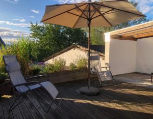 a patio with two chairs and an umbrella on a deck at Waldmomente in Schauren +13 photos