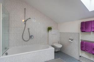 a bathroom with a tub and a toilet and purple towels at Woehrmannhof Apt Birnblüte in Feldthurns +21 photos