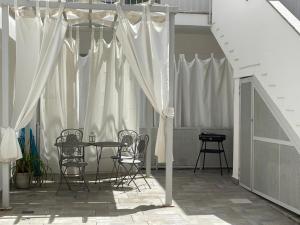 a patio with a table and chairs and white curtains at La casa dei naviganti in Villasimius