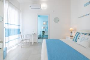a white bedroom with a blue bed and a desk at La casa dei naviganti in Villasimius