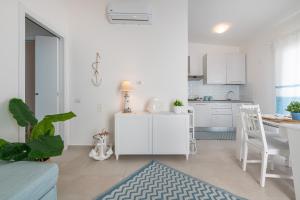 a white living room with a kitchen and a table at La casa dei naviganti in Villasimius +22 photos