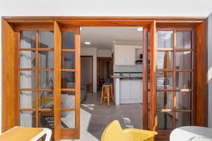 a living room with wooden doors and a kitchen at Playa Delphin 306 in Puerto Naos