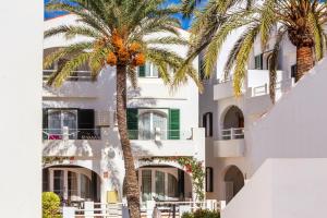 a building with palm trees in front of it at White sands 613 in Arenal d'en Castell