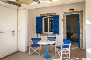 a table and chairs on a patio with blue shutters at Perasma Studios 9 in Kipri