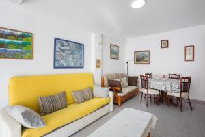 ein Wohnzimmer mit einem gelben Sofa und einem Tisch in der Unterkunft Ca Llaurí in Daimús