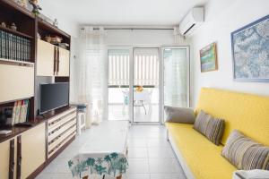 ein Wohnzimmer mit einem gelben Sofa und einem Fernseher in der Unterkunft Ca Llaurí in Daimús