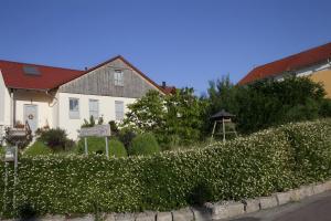 a house and a hedge with flowers in front of it at Ferienwohnung Im Schiller in Wiesenbronn