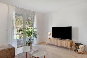 a living room with a flat screen tv on a white wall at Bachblick in Buchenbach