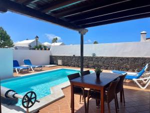 a patio with a table and chairs next to a swimming pool at Villa Gauda in Lanzarote +13 photos