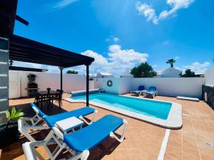 a patio with blue chairs and a swimming pool at Villa Gauda in Lanzarote