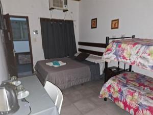 a room with two beds and a table with a tableablish at Hostal AMALAYA in Salta