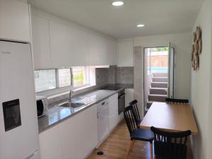 a kitchen with white cabinets and a wooden table at Maia House da Piscina in Folgosa