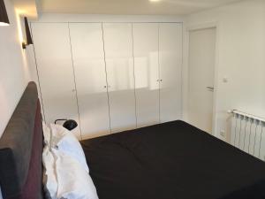 a bedroom with white cabinets and a black bed at Maia House da Piscina in Folgosa
