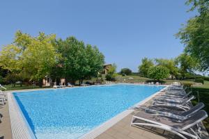 a large swimming pool with lounge chairs and trees at Residenza Le Paolette con piscina in Padenghe sul Garda