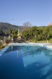a swimming pool with blue water and two chairs at Es Tarongers in Sóller