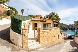 a house with a stone wall next to a street at Villa con Infinity pool in Lloret de Mar