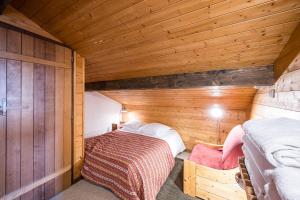 a small room with a bed in a wooden cabin at Chalet Farapreu in Manigod