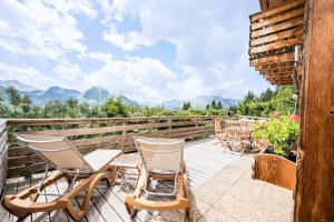 a deck with chairs and tables and mountains in the background at Chalet Farapreu in Manigod