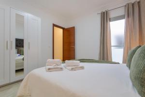 a bedroom with a white bed with towels on it at Apartamento Rolycar 204 in Icod de los Vinos