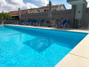 a blue swimming pool with blue chairs and umbrellas at Maia House da Piscina in Folgosa