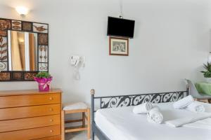 a bedroom with a bed and a dresser and a mirror at Ilias Voula Studios in Kalymnos