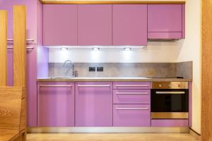 a kitchen with purple cabinets and a sink at Appartamento Tobià in Pozza di Fassa
