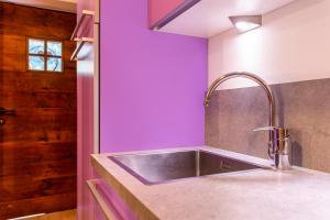 a kitchen with a sink and a purple wall at Appartamento Tobià in Pozza di Fassa +18 photos
