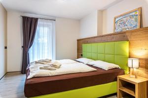 a bedroom with a large bed with a green headboard at Appartamento Tobià in Pozza di Fassa