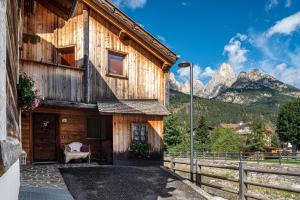 a wooden house with mountains in the background at Appartamento Tobià in Pozza di Fassa