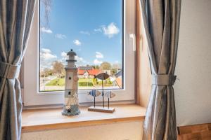 a window with a lighthouse in a room at Ferien mit Hund Blomberg Ostfriesl in Blomberg