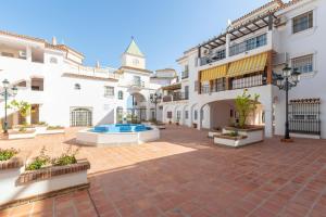 a courtyard of a white building with a clock tower at Cute apartment oceanfront in Benalmádena