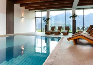 a pool with chairs and tables in a building at Bio Wellnesshotel Pazeider in Marlengo