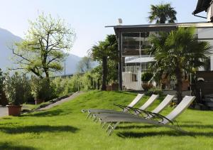a group of white chairs in the grass in front of a house at Bio Wellnesshotel Pazeider in Marlengo