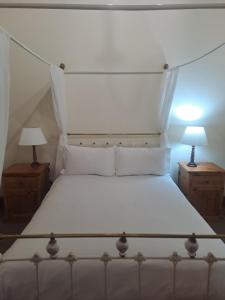 a bedroom with a white bed with two night stands at De Kothuize 10 in Graaff-Reinet +1 photo
