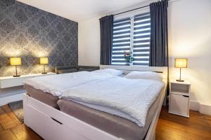 a bedroom with a large white bed with two lamps at Ferienwohnung Gartencity in Geesthacht