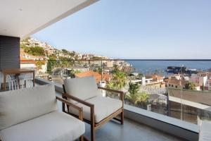 a balcony with two chairs and a view of the ocean at Casa Castanheta in Câmara de Lobos