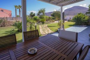 a wooden table and chairs on a patio with mountains at Tramonto A Nordovest in Favignana