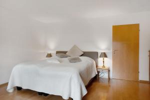 a bedroom with a white bed and a wooden floor at Secret Garden in Müllheim